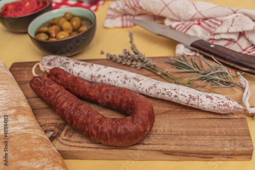 Fuets Catalan dry sausages. Set of spanish sausages and dry cured meat chistorra, chorizo, salchichon, fuet, olives, rosemary, chili peppers on a wooden background. top view.