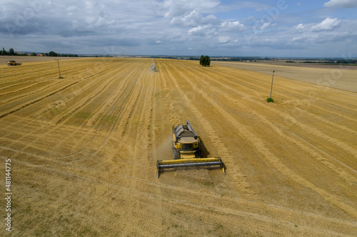 Yellow combine harvester harvests wheat from the field. Photo from a drone.