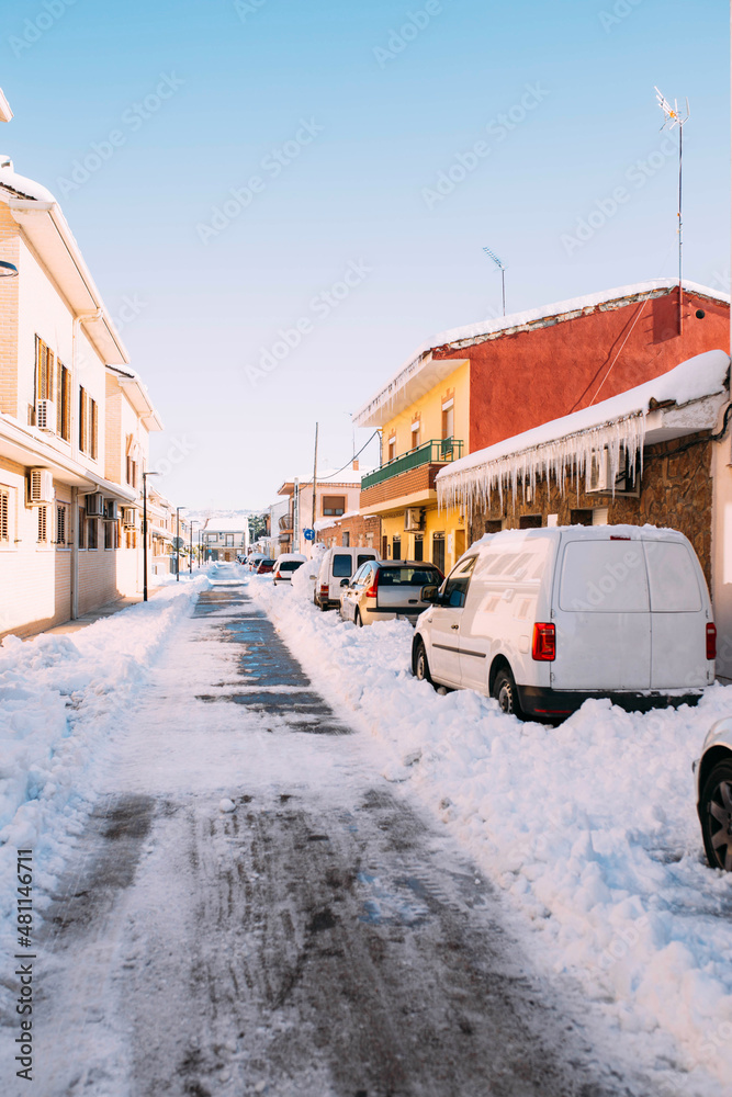 Fototapeta premium Street full of ice after a heavy snowfall with cars buried under the snow. Winter season.