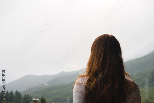Young redhead woman admires mountains in autumn, back view.