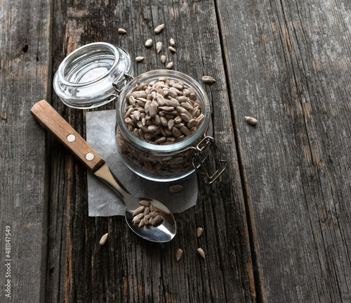 Peeled sunflower seeds glass jar with a spoon on an old wooden table with space for text. Top view