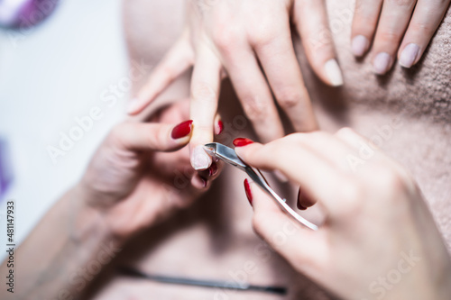 Close up image of manicure process  removal of nail cuticle nail with nail clipper. Focus on fingernail.