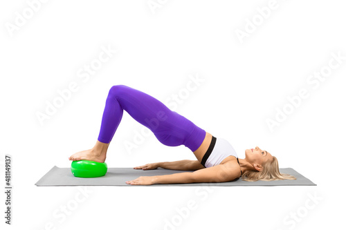 Classic pilates with props. Athletic woman practice shoulder bridge with a small fit ball under her feet, isolated on white.