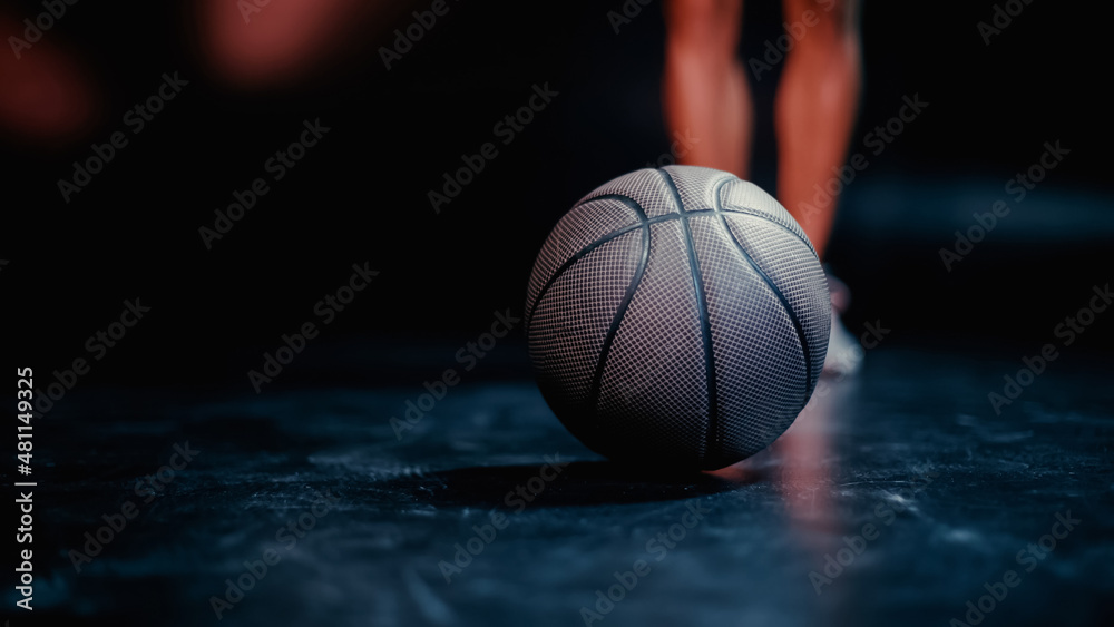 partial view of blurred sportsman standing near basketball on dark background