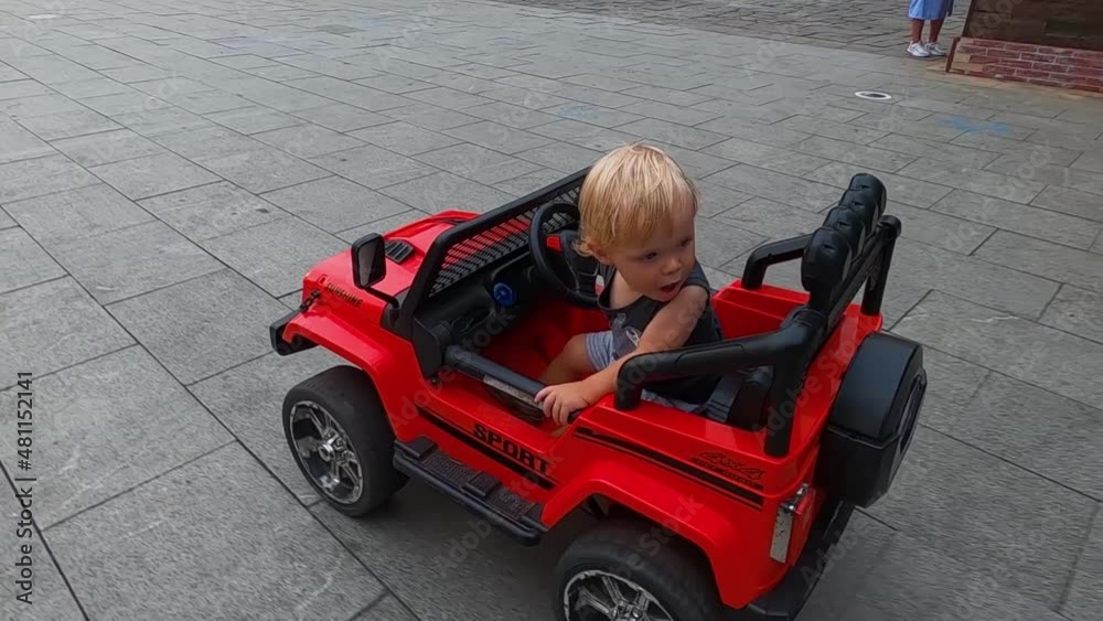 little boy blonde rides by himself in a children's electric car little boy blonde rides by himself in a children's electric car