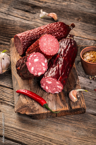 traditional European cuisine. Salami Sausage Stick with basil, dried meat, close-up. on wooden background. cold meats.