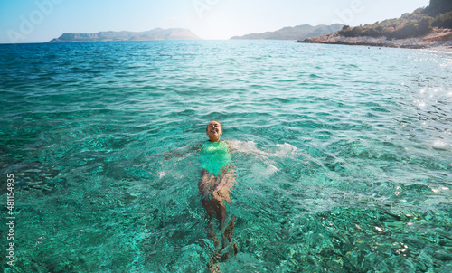 Smiling woman lying on her back floating in the sea water, relaxing on vacation, Travelling tour in Turkey
