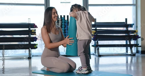 Little daughter carries mom a sports mat for exercising in the gym. Prores.