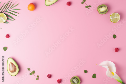 Creative tropical background made from fresh fruits and palm leaves on pink. Flat lay, copy space.