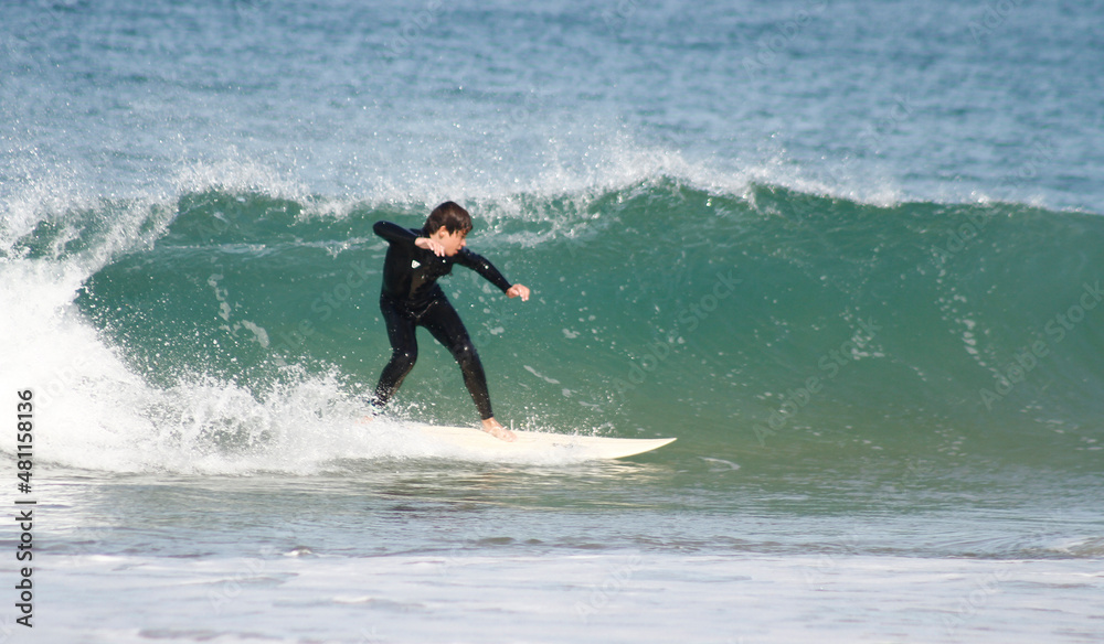 Happy teenager surfing in the Atlantic Ocean