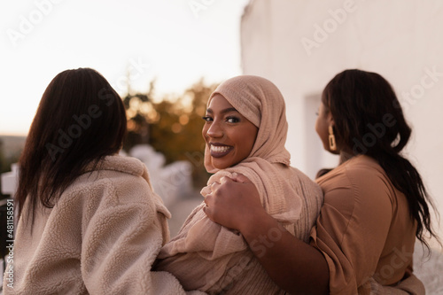 Fotografie, Obraz Happy muslim woman walking with her friends outdoors