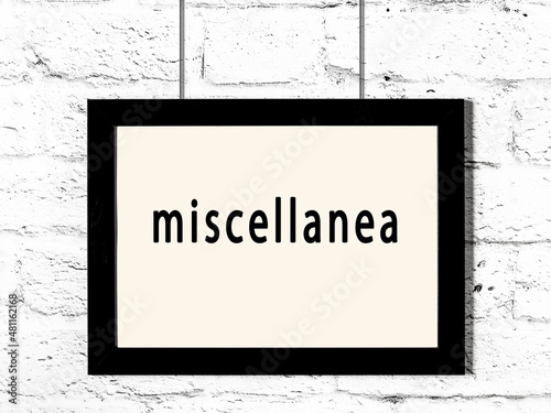 Black frame hanging on white brick wall with inscription miscellanea