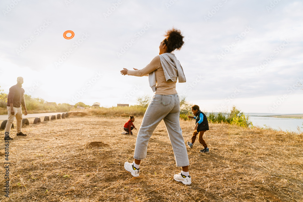 Black family laughing and playing with frisbee during walking Black family laughing and playing with frisbee during walking