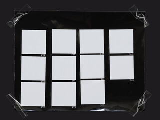 macro photo of black and white hand copy contact sheet with 11 empty film frames fixed by transparent sticker tape on dark background.
