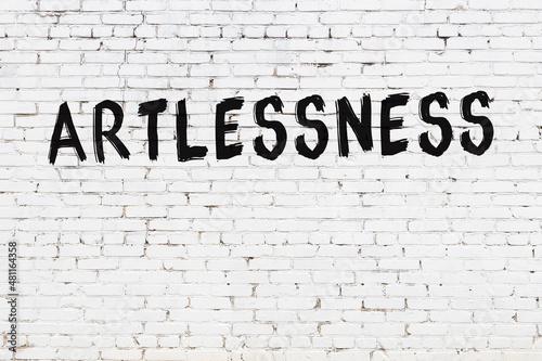 White wall with black paint inscription artlessness on it