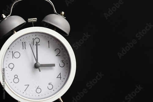 White alarm clock in dark background with copy space. Time concept.