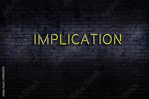 Neon sign. Word implication against brick wall. Night view photo