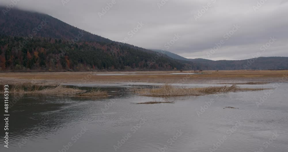 Gloomy weather above pristine intermittent Cerknica lake in Slovenia. Important wetland in karst environment. Autumn or fall season. Left pan, real time