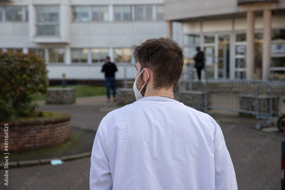 vue de dos d'un aide soignant, infirmier ou médecin en blouse blanche, portant un masque de protection contre le virus Covid 19 et qui va travailler à l'hôpital vue de dos d'un aide soignant, infirmier ou médecin en blouse blanche, portant un masque de protection contre le virus Covid 19 et qui va travailler à l'hôpital