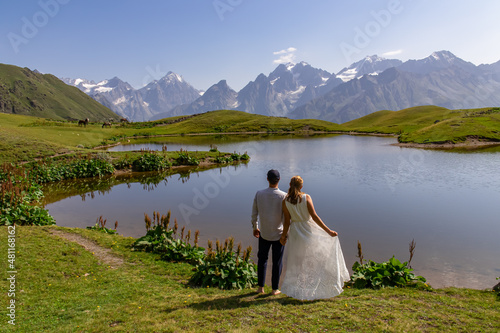 Bride and groom getting married at the Koruldi Lake with a dream like view on mountains near Mestia in the Greater Caucasus  Upper Svaneti  Country of Georgia. Horses at the water shore. Fairytale