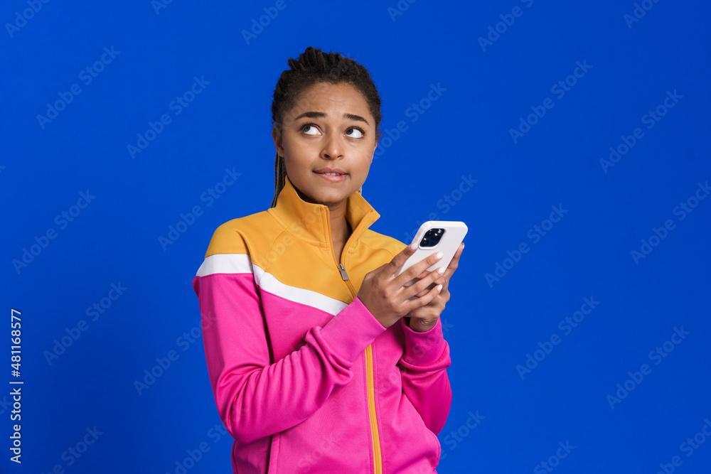 Black young woman looking upward while using mobile phone Black young woman looking upward while using mobile phone