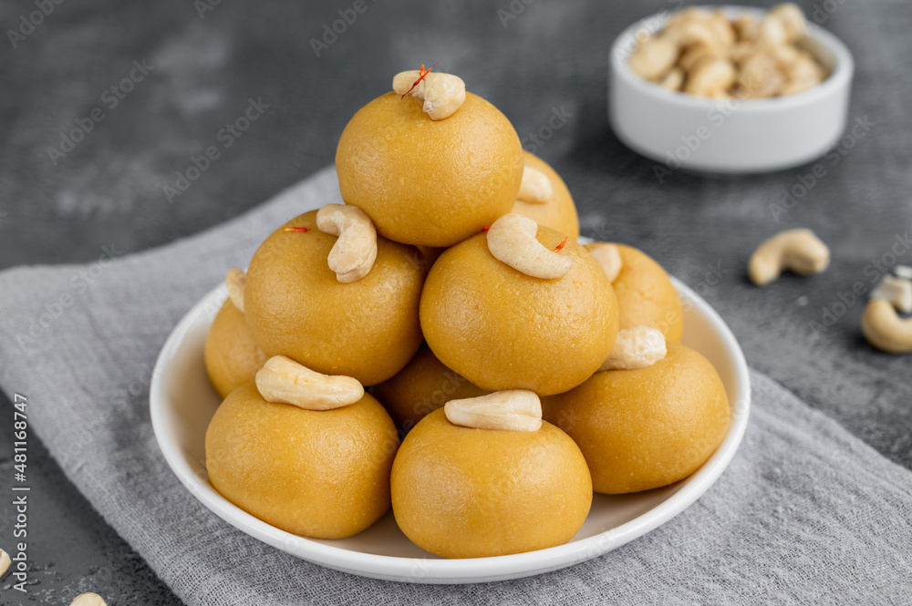 Indian sweets Besan Laddu or Laddoo on a plate on a concrete bacground. Roasted chickpea flour with ghee and sugar. Selective focus. Indian sweets Besan Laddu or Laddoo on a plate on a concrete bacground. Roasted chickpea flour with ghee and sugar. Selective focus.