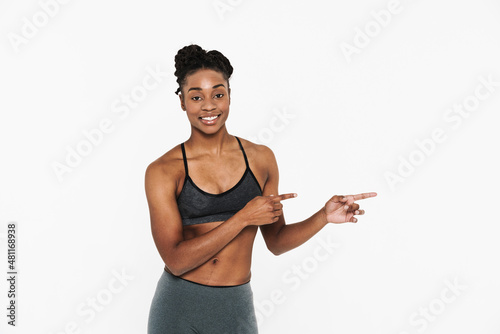 Young black sportswoman smiling and pointing finger aside