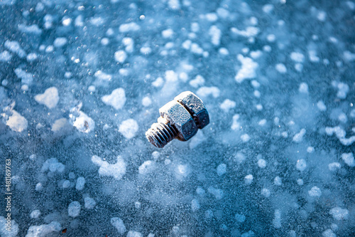 Frozen threaded bolt on blue ice lake