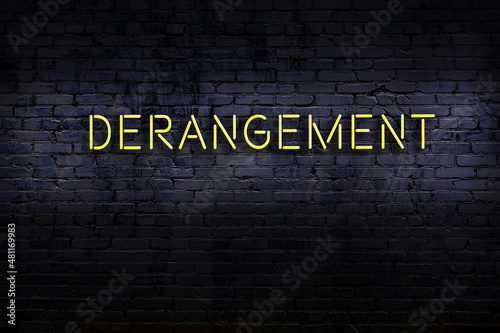 Night view of neon sign on brick wall with inscription derangement