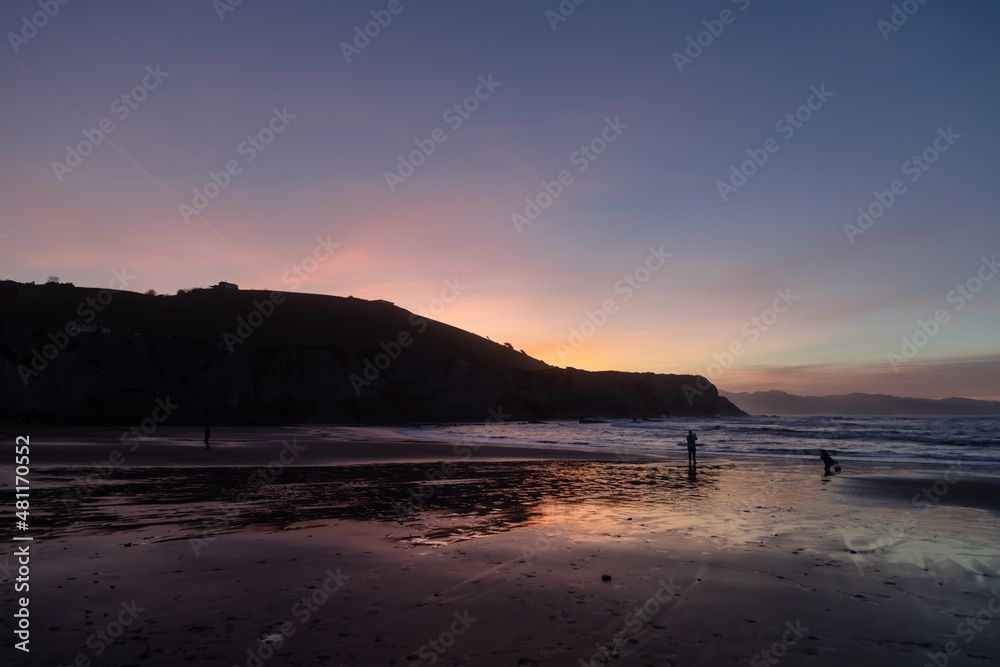 sunset in zumaia beach with people in backlight
