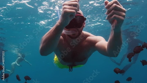 Man swims underwater with fish. Tropical snorkeling in Maldives photo