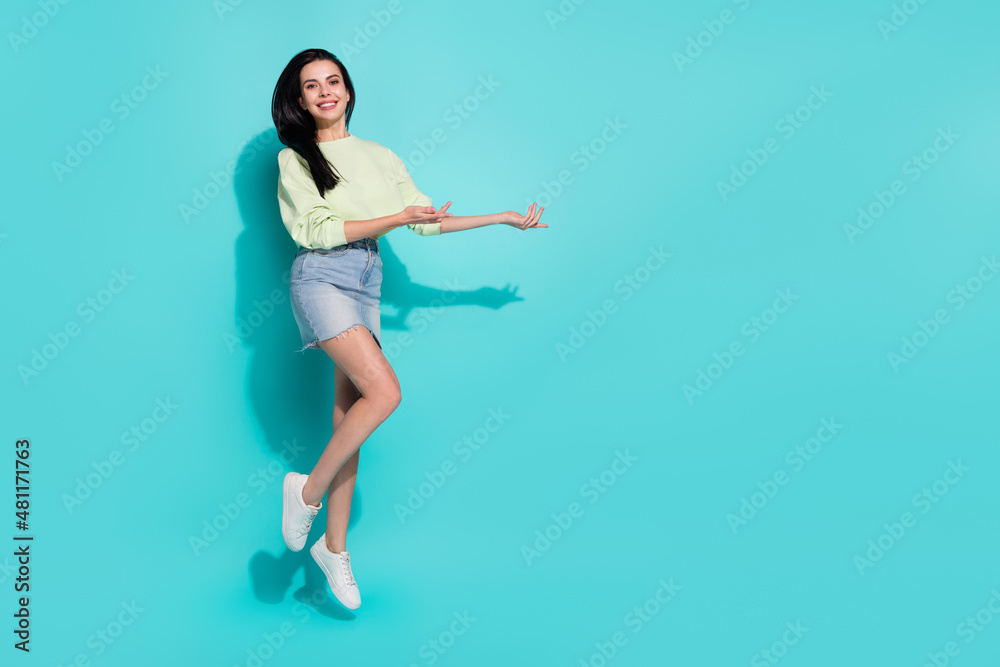 Full length photo of lady promoter jump hand present empty space ads discounts isolated over cyan color background Full length photo of lady promoter jump hand present empty space ads discounts isolated over cyan color background