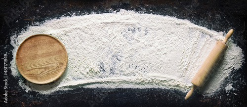 Fotografija Abstract baking background with the rolling pin and flour on dark table