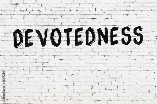 White wall with black paint inscription devotedness on it