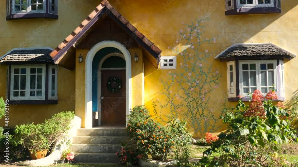 A yellow rustic house with blooming flowers, green bushes and pretty windows. Provence style cottage on sunset light. Close up. Recovering in countryside from the noisy metropolis A yellow rustic house with blooming flowers, green bushes and pretty windows. Provence style cottage on sunset light. Close up. Recovering in countryside from the noisy metropolis