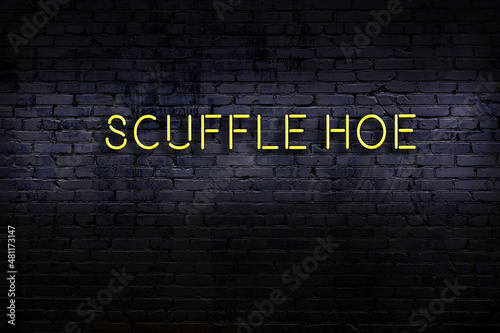 Neon sign. Word scuffle hoe against brick wall. Night view