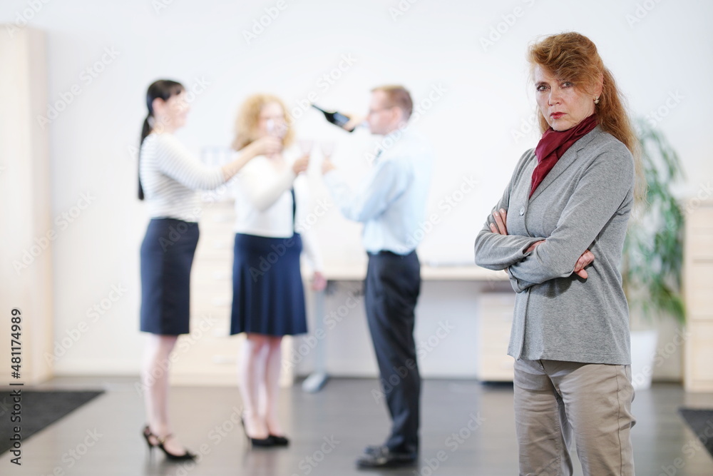 3 Büroangestellte feiern im Hintergrund, während die Chefin böse vorne steht 3 Büroangestellte feiern im Hintergrund, während die Chefin böse vorne steht