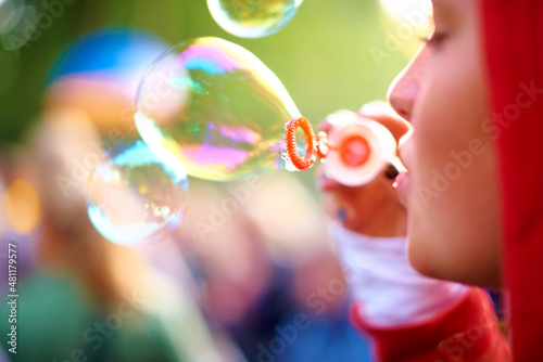 Blowing bubbles. A young woman blowing bubbles outside - profile.