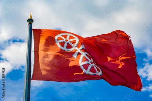Great close-up view of the flag of Mainz, the capital and largest city of Rhineland-Palatinate, Germany. It consists of a silver wheel, the so called Mainzer Rad, with six spokes on a red background.