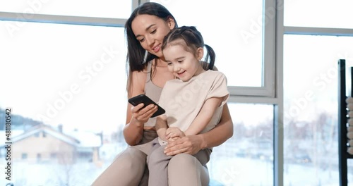 A little girl sits on her mother's lap and looks at the phone. Gym.