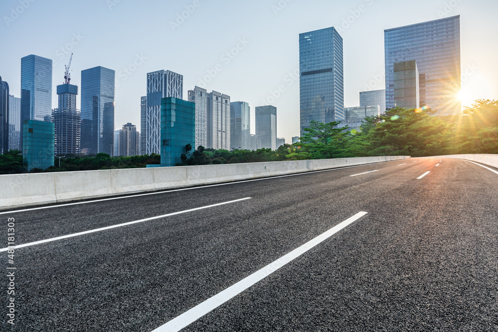 Asphalt road and city skyline with modern commercial office buildings in Shenzhen at sunrise, China.