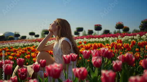 Young woman smiling in bright flower garden. Woman profile in flower background.