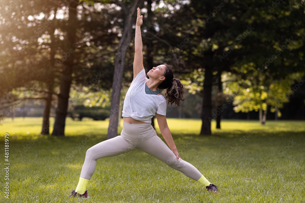 Young female practising yoga in public park at sunrise