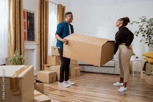 A young couple in love carry boxes of packed belongings out of their house while moving to a new apartment, buying a house, renting a flat, having fun fooling around at work © ABCreative