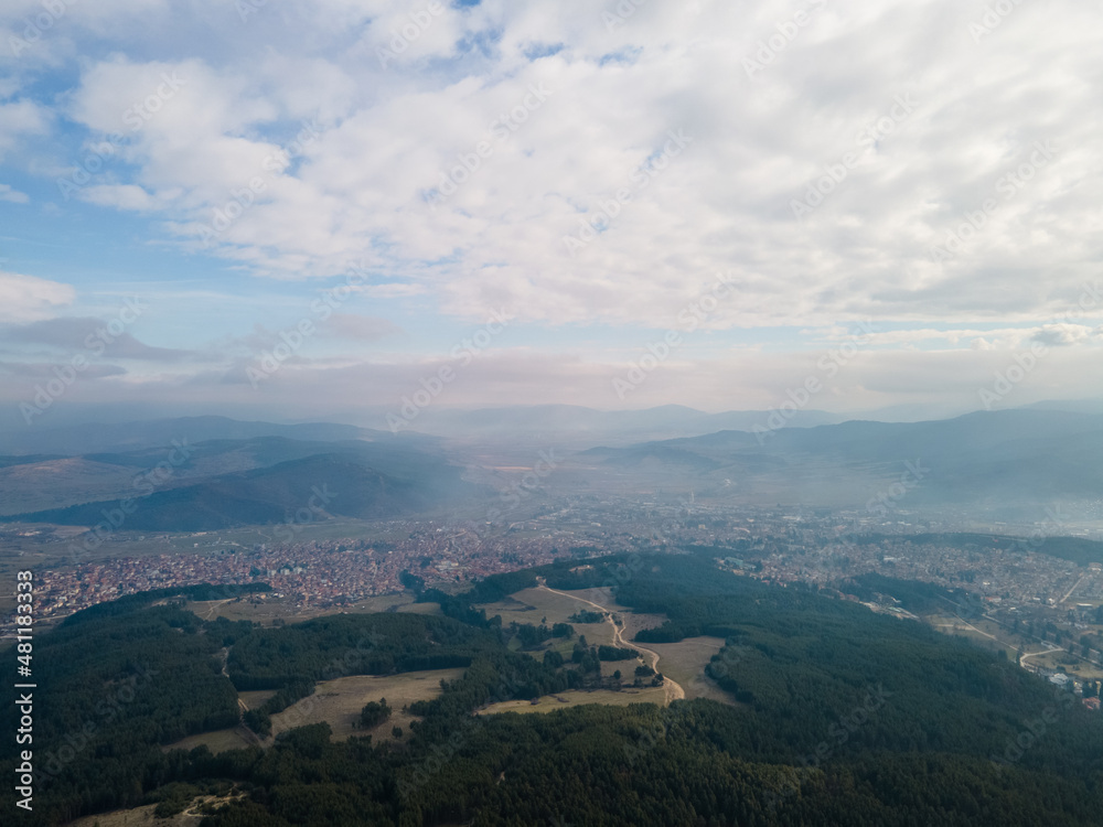 Aerial view of clouds over the city between green mountains