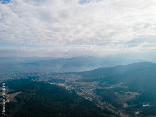 Aerial view of clouds over the city between green mountains