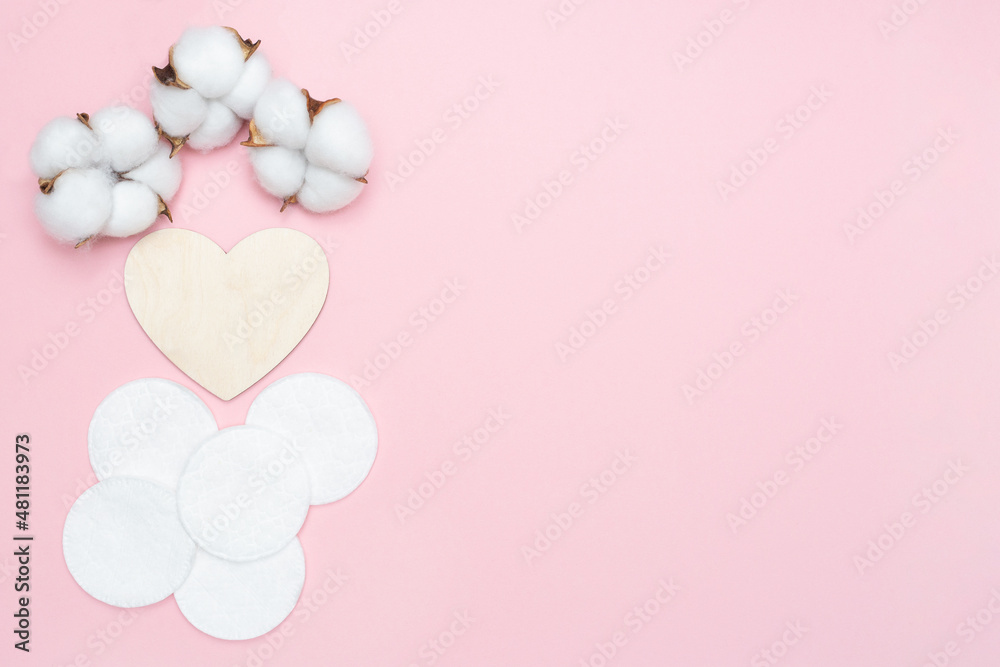 Cotton pads and wooden heart. Cosmetic pad and cotton flowers. Pink pastel background. Place for text. Copy space. Flat lay. Beauty and hygiene Cotton pads and wooden heart. Cosmetic pad and cotton flowers. Pink pastel background. Place for text. Copy space. Flat lay. Beauty and hygiene