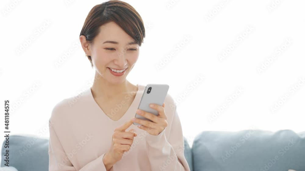 ソファーに座りながらスマートフォンを使う若い女性
