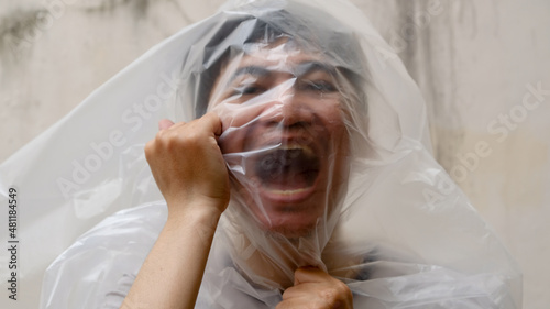 Young Man with a black transparent bag on his head. suffocate. face in a plastic bag, strangulation. 
environmental pollution