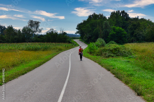 Rear view of a woman walking along a rural road near Donja Cadjavica, Bosnia and Herzegovina photo